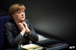 German Chancellor Angela Merkel listens to Gregor Gyisi of the Left party answer her speech on the government's policy on Ukraine at the Bundestag, Germany's lower house of parliament in Berlin on March 13, 2014.