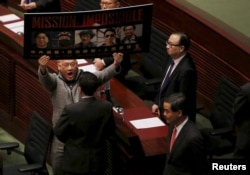 FILE - Pro-democracy lawmaker Albert Chan, carrying portraits of five missing booksellers from a local bookstore, shouts to Hong Kong Chief Executive Leung Chun-ying as he enters the Legislative Council chamber in Hong Kong, China, Jan. 13, 2016.