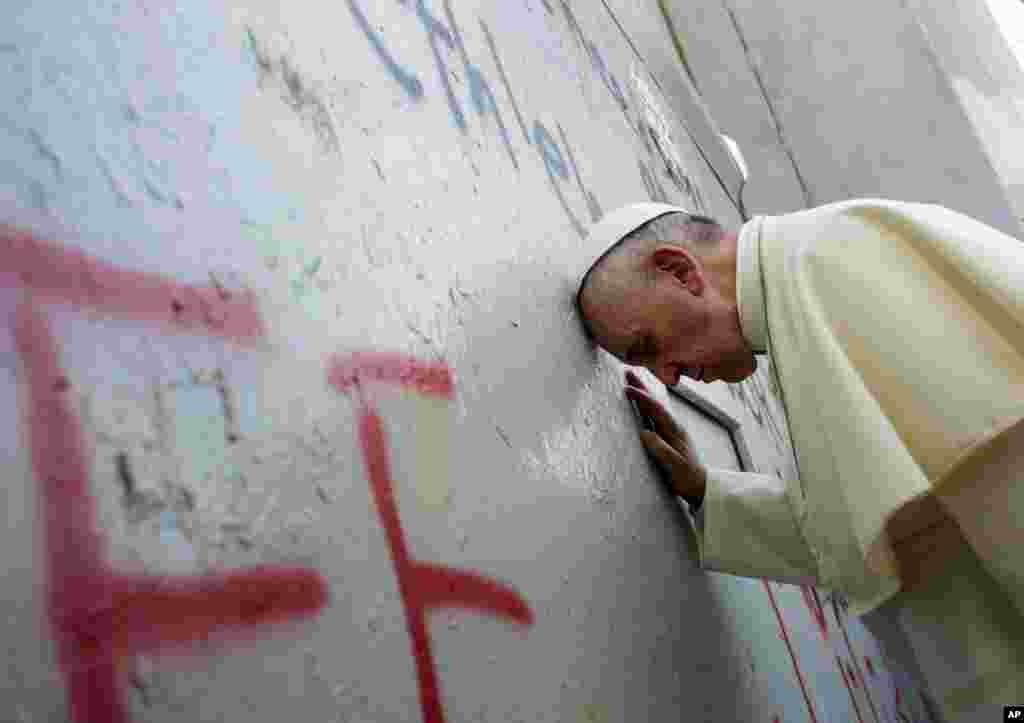 Pope Francis touches the wall that divides Israel from the West Bank.