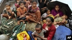 In this June 13, 2012 file photo, Rohingya Muslims who fled Burma to Bangladesh to escape religious violence, sit in a boat after being intercepted crossing the Naf River by Bangladeshi border authorities in Taknaf, Bangladesh.