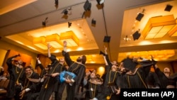 Graduates throw their caps at the conclusion of the Commencement Ceremony for Hult International Business School