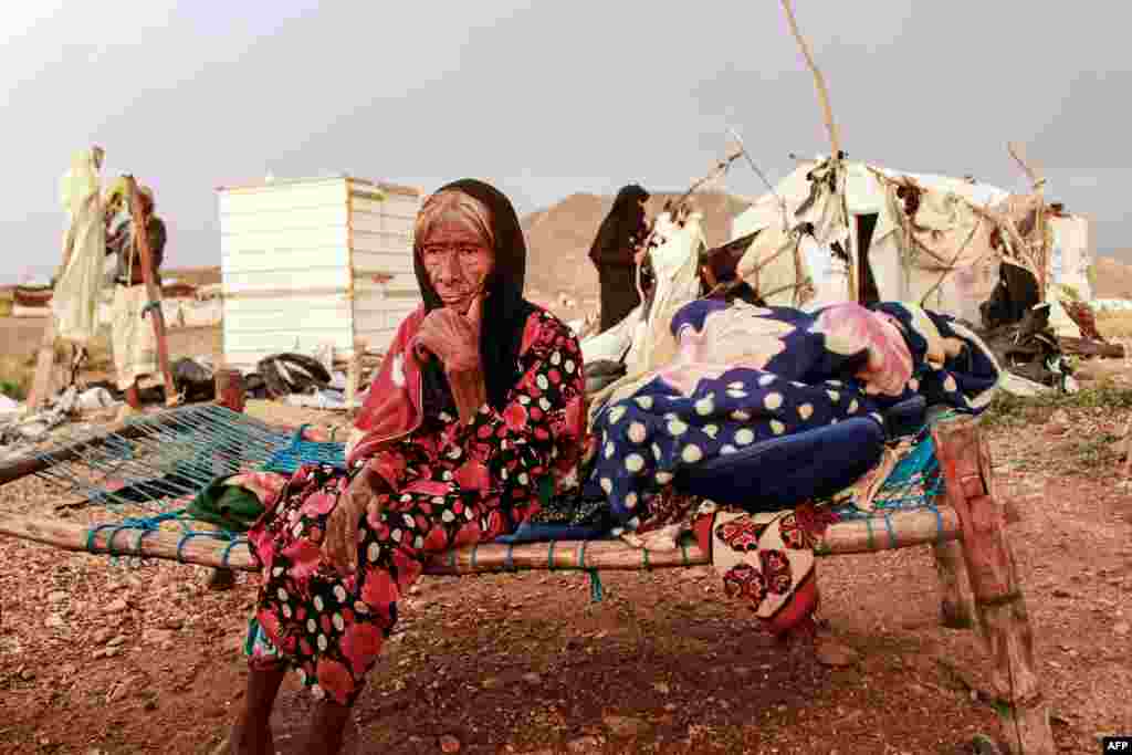 An elderly woman sits on a make-shift bed as people try to salvage tents damaged by torrential rain, at a camp for Yemenis displaced by conflict in the northern Hajjah province, Sept. 30, 2020.