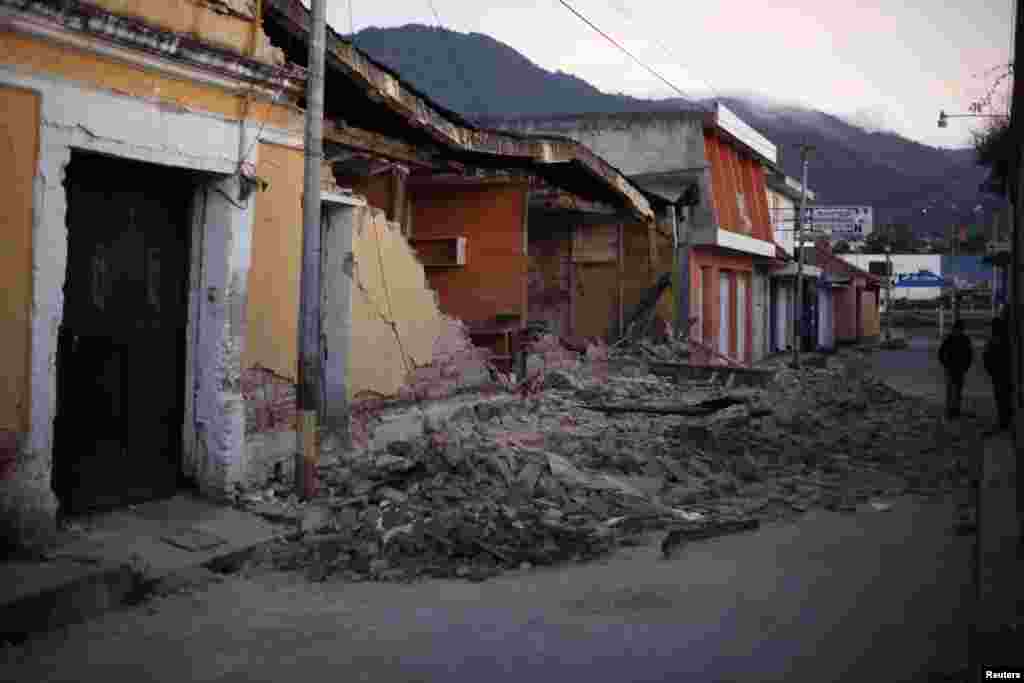 Two men walk past damaged houses after a 7.4-magnitude earthquake on the streets of San Marcos, Guatemala, November 8, 2012. 