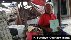 Haji Fuadzi, resident of Pemenang County, North Lombok, holding up his land deed he found in the rubble of his concrete house.