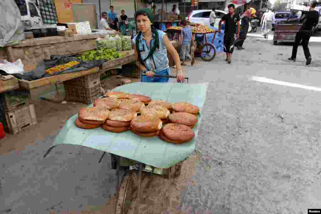 A boy sells sweet bread on the first day of the holy fasting month of Ramadan, in the Al-Fardous neighborhood of Aleppo, June 29, 2014. 