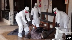 Health workers in protective gear move the body of a person that they suspect died from the Ebola virus in Monrovia, Liberia.