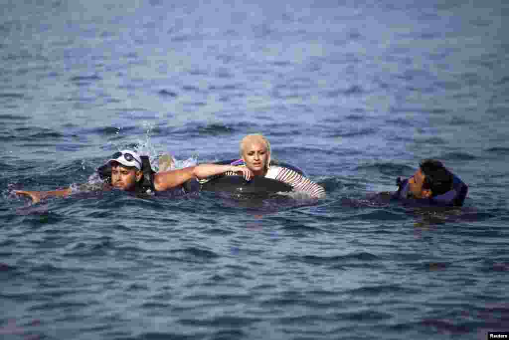 Syrian refugees swim towards a beach after abandoning a dinghy with a broken engine on the Greek island of Lesbos, Sept. 9, 2015. Greece asked the European Union for aid to prevent it being overwhelmed by refugees, as a minister said arrivals on Lesbos had swollen to three times as many as the island could handle.