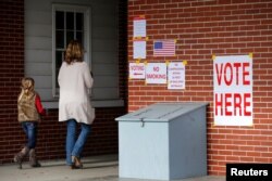 Anna Atkinson walks into a polling station with her 8-year-old daughter Tori, in Gallant, Alabama, Dec. 12, 2017.