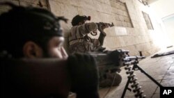 Free Syrian Army fighters aim their weapons at the entrance of a building during heavy clashes with government forces in Aleppo, Syria, December 5, 2012.