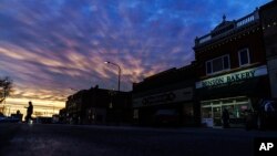 FILE - A customer carries a box of baked goods from a bakery at sunrise in Benson, Minn., Dec. 1, 2021.