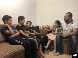 In this Sunday, Sept. 1, 2019 photo, Syrian refugee Zahir Hamshari sits with his children in his rented apartment in east Amman, Jordan. Seven years after fleeing the civil war in his homeland, Hamshari’s life is filled with questions and doubts. (AP)