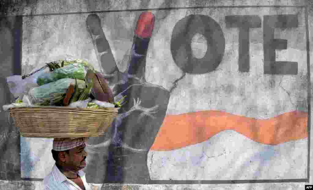 A vegetable vendor walks past graffiti urging Indians to vote, in Mumbai. Five Indian states representing more than 160 million voters will go to the polls, a key test for the prime minister after his shock currency move.