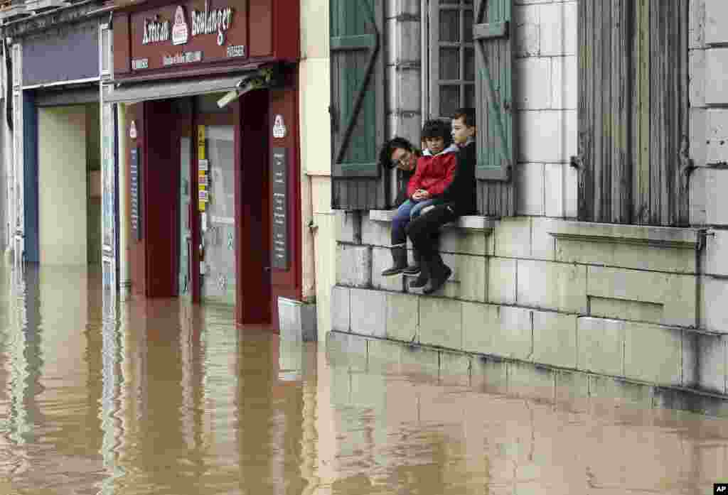 A mother and her children watch from their house the level of flooded water caused by heavy rain and thunder storms, in Salies-de-Bearn, southwestern France.