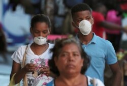 Las personas usan máscaras protectoras después de un brote del coronavirus en la ciudad de Panamá.