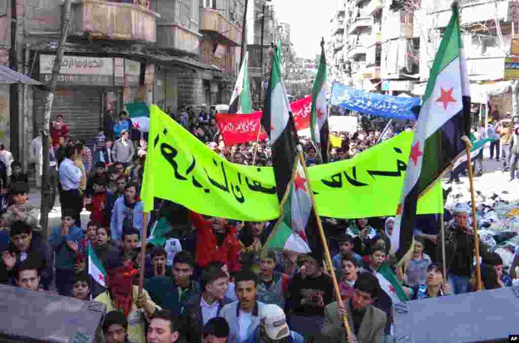 Anti-Syrian regime protesters hold banners and flags during a demonstration in the neighborhood of Bustan Al-Qasr in Aleppo, March 29, 2013. 