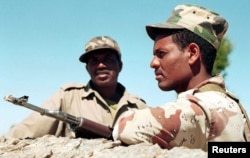 FILE - Two Eritrean soldiers keep a watchful eye on the disputed Eritrean/Ethiopian border from a vantage point on top of Eigar Mountain, near Tsorona, Eritrea, Jan. 25, 1999.