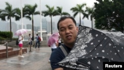A man braves the wind at the Golden Bauhinia Square as Typhoon Utor approaches Hong Kong, August 14, 2013.