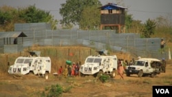 Internally displaced people walk next to U.N. vehicles on the perimeter of a protection of civilians (POC) site in Juba, South Sudan, Dec. 5, 2016. (J. Craig/VOA)