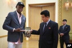 FILE - Former NBA basketball star Dennis Rodman presents a copy of "Trump: The Art of the Deal" to North Korean Sports Minister Kim Il Guk, June 15, 2017, in Pyongyang, North Korea.