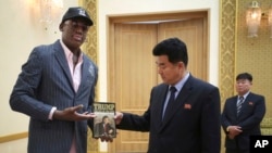 Mantan bintang basket NBA Dennis Rodman memberikan sebuah buku berjudul "Trump: The Art of the Deal" kepada Menteri Olahraga Korea Utara, Kim Il-guk, Kamis, 15 Juni 2017, di Pyongyang, Korea Utara. (Foto AP / Kim Kwang Hyon)