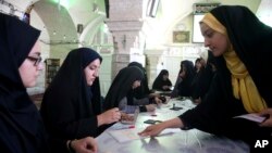 A voter gets ballots to cast in the presidential and municipal council election at a polling station in the city of Qom, 78 miles (125 kilometers) south of the capital Tehran, Iran, May 19, 2017.