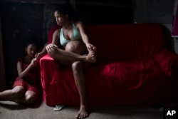 FILE - In this Jan. 29, 2016 photo, Tainara Lourenco, who is five months pregnant, sits inside her house at a slum in Recife, Brazil.
