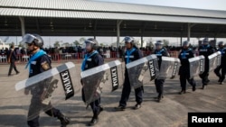 Riot policemen walk around during a registration of election candidates at a bus terminal centre near the Government complex in Bangkok, Dec. 28, 2013.