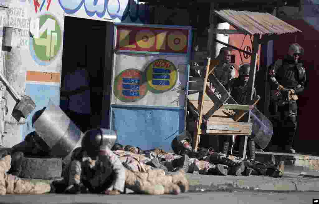 National police take cover as gun shots ring out at the end of a ceremony marking the 212th anniversary of the assassination of independence hero Gen. Jean-Jacques Dessalines in Port-au-Prince, Haiti. At least three people were injured when shots were fired at the ceremony.