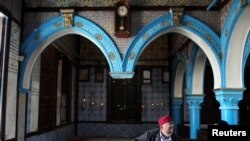 Deux hommes assis près d'une synagogue à Ghriba, la synagogue la plus vieille d'Afrique. Le 3 mai 2018