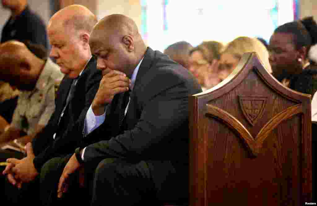 O Senador americano Tim Scott (centro) baixa a sua cabeça em reverência ao orar durante uma vigília realizada na Igreja Morris Brown AME em Charleston, Carolina do Sul, 18 de Junho, 2015.