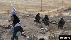 Palestinian protesters throw stones at Israeli soldiers in the West Bank town of Hawara near Nablus July 25, 2014.