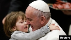 FILE - Pope Francis holds a child as he leads the weekly audience in Paul VI's hall at the Vatican, Jan. 20, 2016.