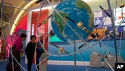 FILE - Visitors look at a display of satellite technologies at an exhibition highlighting China's achievements under five years of Xi's leadership at the Beijing Exhibition Hall in Beijing, China, Oct. 19, 2017. 