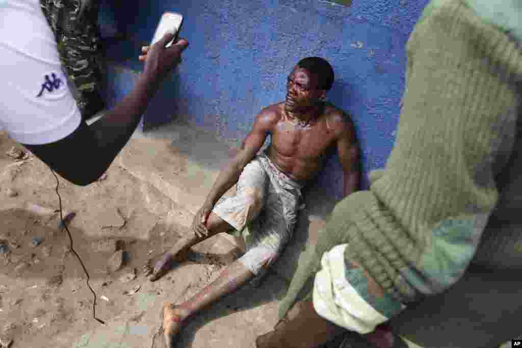 Jean Claude Niyonzima, a suspected member of the ruling party's Imbonerakure youth militia, sits under soldiers' protection from a mob of demonstrators after he came out of hiding in a sewer in the Cibitoke district of Bujumbura, Burundi, May 7, 2015. 