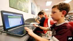 In this May 8, 2019, photo, third-grade student Miles Stidham uses an East Webster High School laptop to do homework in Maben, Mississippi.(AP Photo/Rogelio V. Solis)