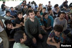 FILE - Suspected Uighurs from China's troubled far-western region of Xinjiang, sit inside a temporary shelter after they were detained at the immigration regional headquarters near the Thailand-Malaysia border in Hat Yai, Songkla, March 14, 2014.