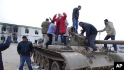 Residents stand on a tank inside a security forces compound in Benghazi, Libya, February 21, 2011