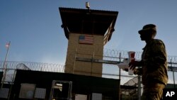 FILE - In this June 5, 2018 photo, reviewed by U.S. military officials, a task force member walks past the Camp 6 detention facility at the Guantanamo Bay U.S. Naval Base, Cuba. 