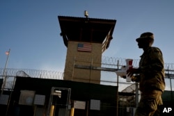 FILE - In this June 5, 2018 photo, reviewed by U.S. military officials, a task force member walks past the Camp 6 detention facility at the Guantanamo Bay U.S. Naval Base, Cuba.