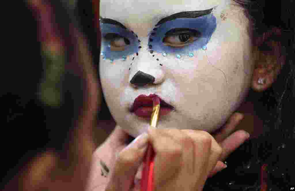 Filipino girl Mikaela Rayll Mangahas has her make-up done as she attends a Halloween event in Manila. 