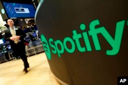 FILE - A trading post sports the Spotify logo on the floor of the New York Stock Exchange, April 3, 2018.