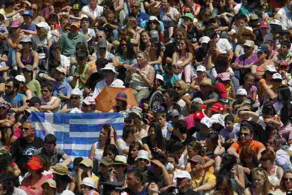 Spectators hold a Greek national flag, during the lighting of the Olympic flame ceremony.