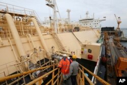 Workers board large-sized liquefied natural gas (LNG) carriers under construction at the Daewoo Shipbuilding and Marine Engineering facility in Geoje Island, South Korea, Dec. 7, 2018.