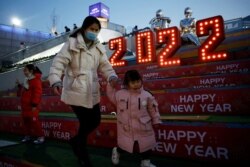 Seorang perempuan mengenakan masker pada Malam Tahun Baru di sebuah pusat perbelanjaan di Beijing, China, 31 Desember 2021. (Foto: REUTERS/Florence Lo)