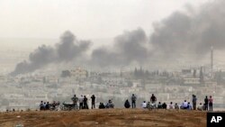 People on a hilltop watch smoke rising from a fire caused by a strike in Kobani, Syria, during fighting between Syrian Kurds and the militants of Islamic State group, on the outskirts of Suruc, at the Turkey-Syria border, Oct. 11, 2014.