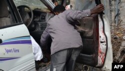 A resident tries to remove the remains of the driver of the female MP and former singer Saado Ali Warsame after gunmen opened fire at her car on July 23, 2014 killing her and her driver in Mogadishu. 