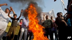 Pakistani Christians chant slogans after they burn a tire during a demonstration demanding that the government rebuild their homes after they were burned down following an alleged blasphemy incident, in Islamabad, Pakistan, March 10, 2013.