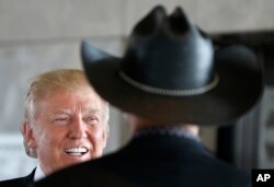 FILE - Republican presidential nominee Donald Trump talks with with Milwaukee County Sheriff David Clarke Jr., right, as he visits the Milwaukee County War Memorial Center on a campaign stop in Milwaukee, Wis., Aug. 16, 2016.