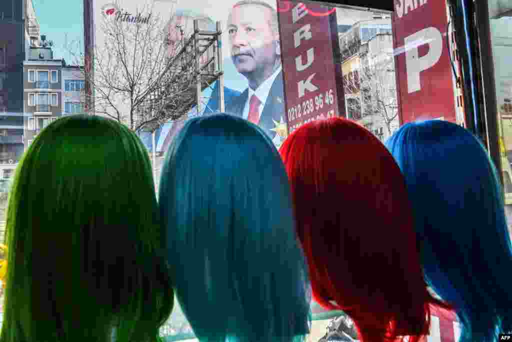 A giant election poster of the Turkish President covering the facade of a building is seen from a shop's window where wig models are displayed, in Istanbul on March 25, 2019, ahead of the March 31 local elections.