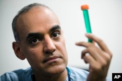 Surgeon Dr. Sunil Singhal poses for a photograph with a vial of fluorescent dye